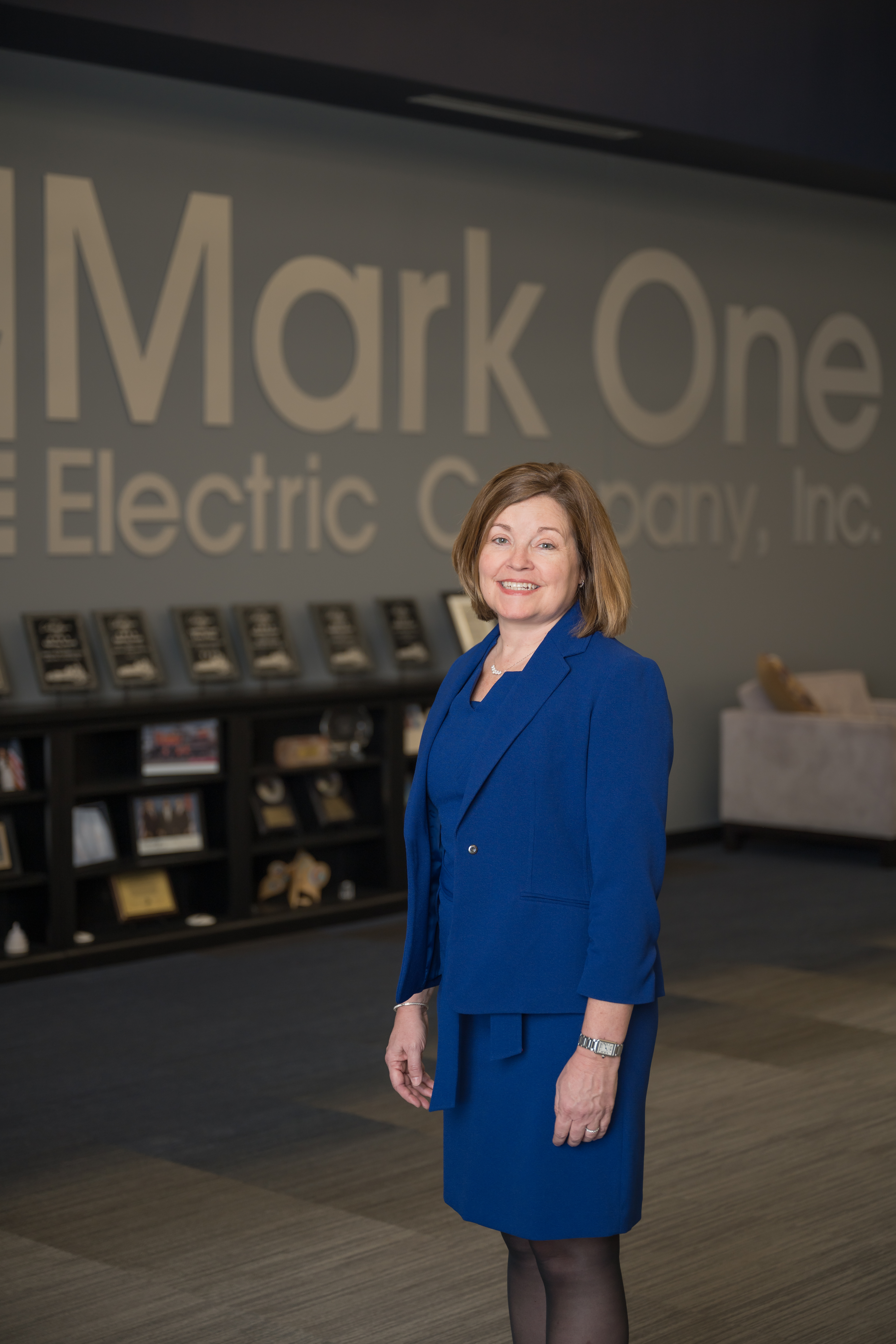 Angie McElhaney stands posing in the lobby of the Mark One Electric office