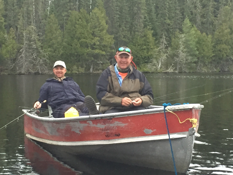 Rob Cleavinger with his father on a fishing boat on a lake surrounded by a mature forest of trees